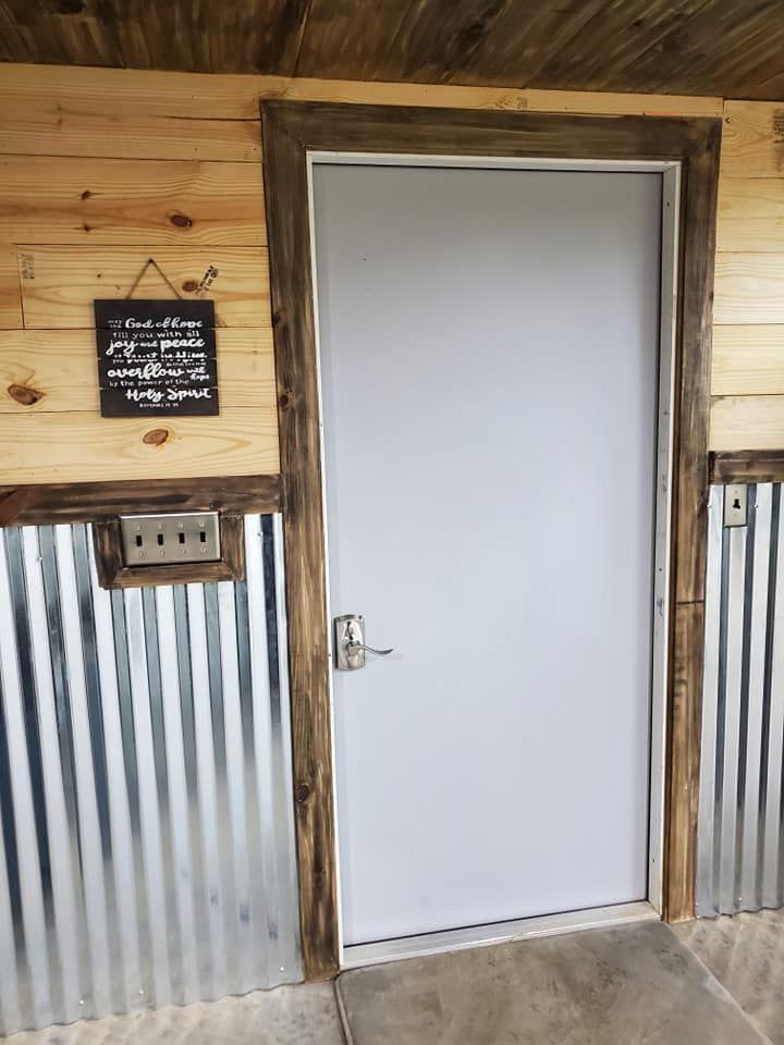 A white door is surrounded by wooden walls and a metal wall.