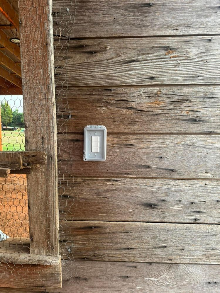 There is a light switch on the side of a wooden building.