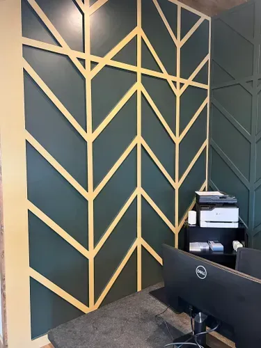 A dell computer is sitting on a desk in front of a green wall.