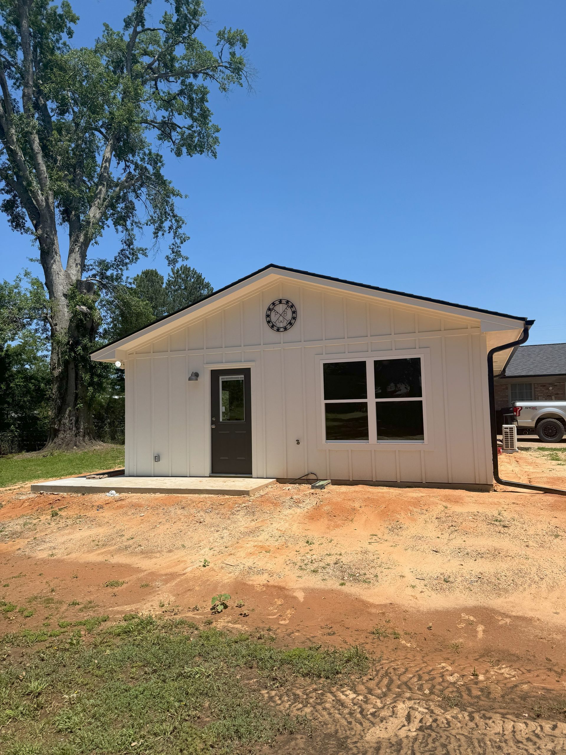 A small white house is sitting in the middle of a dirt field.