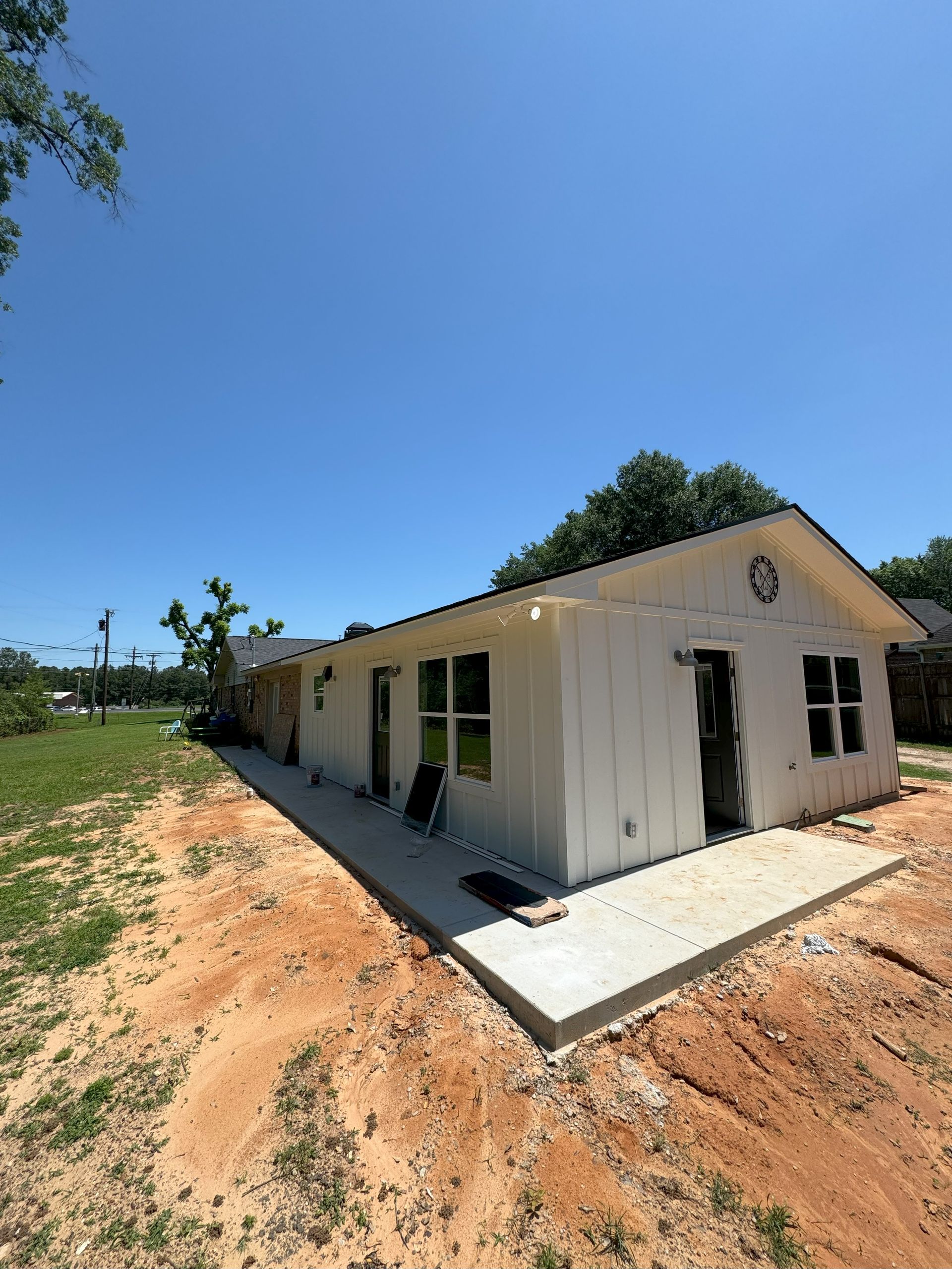 A white house is sitting in the middle of a dirt field.