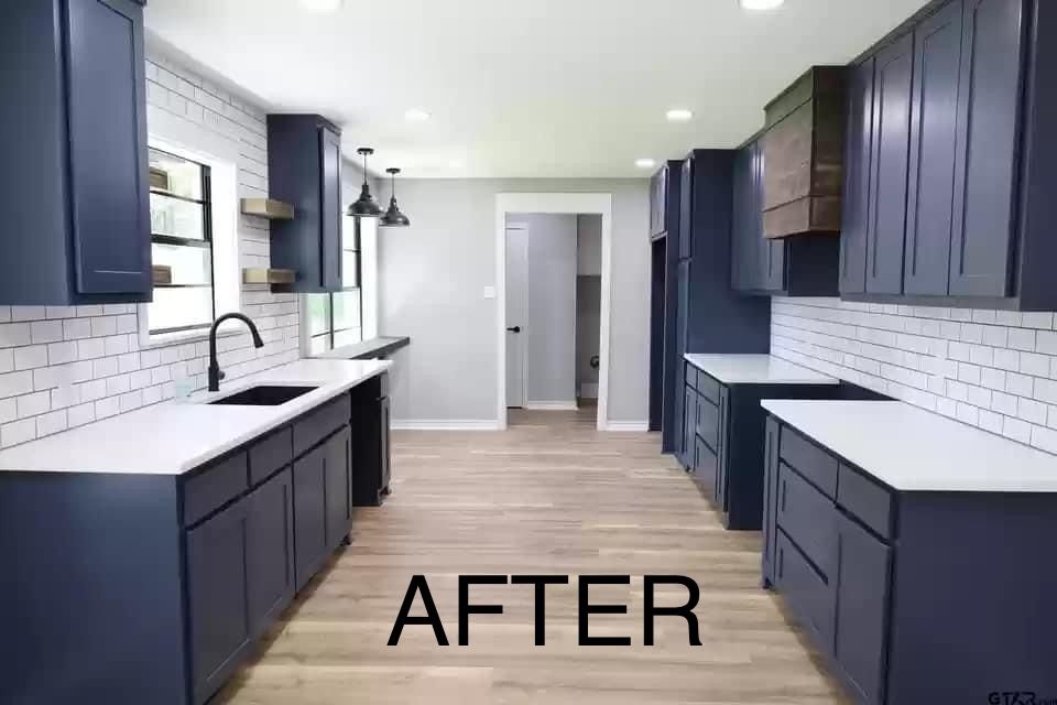 A kitchen with blue cabinets and white counter tops is shown after being remodeled.