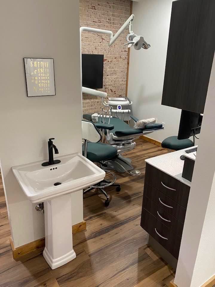 A dental office with a sink and a dental chair.