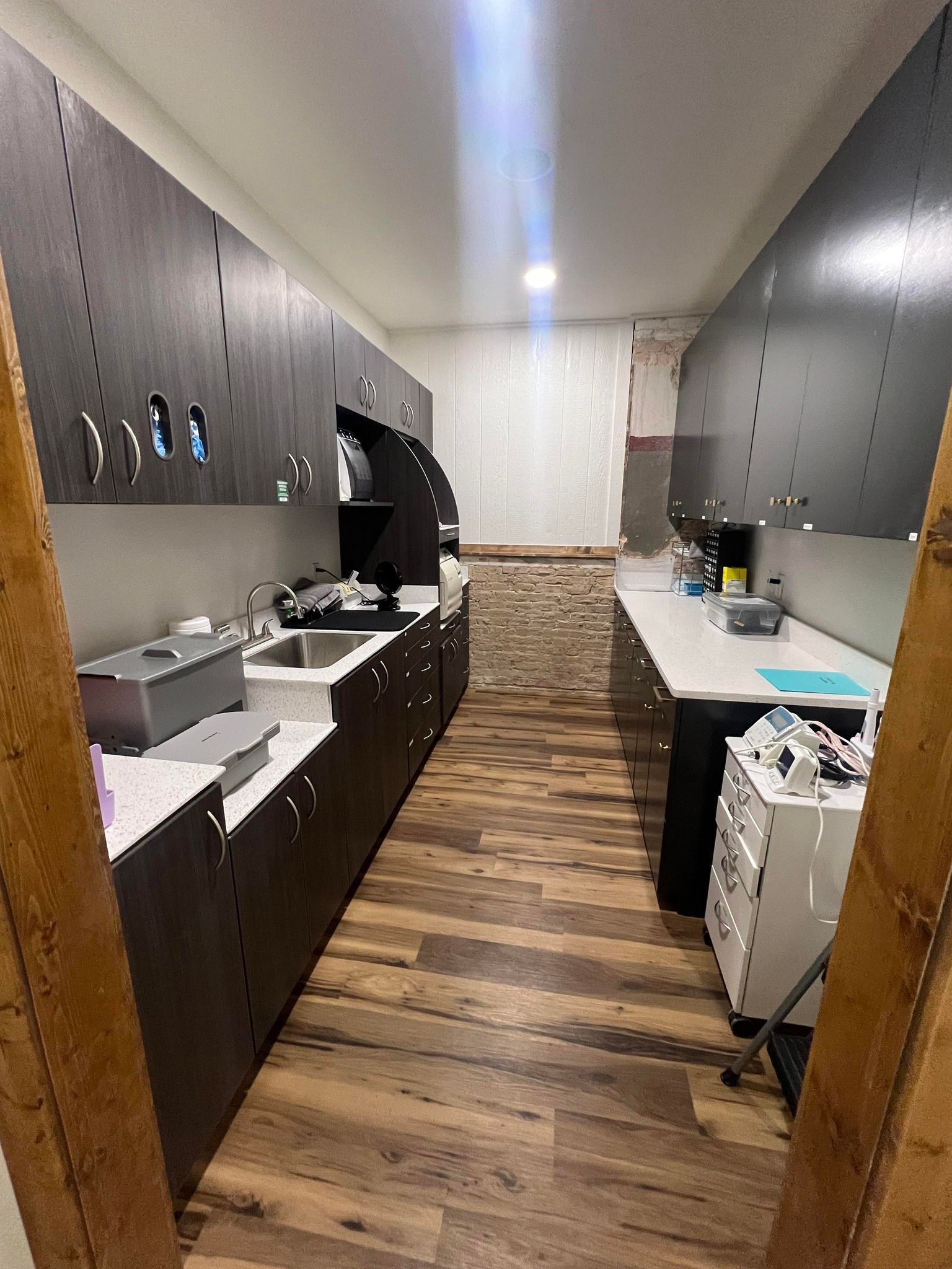 A kitchen with wooden floors and cabinets and a sink.