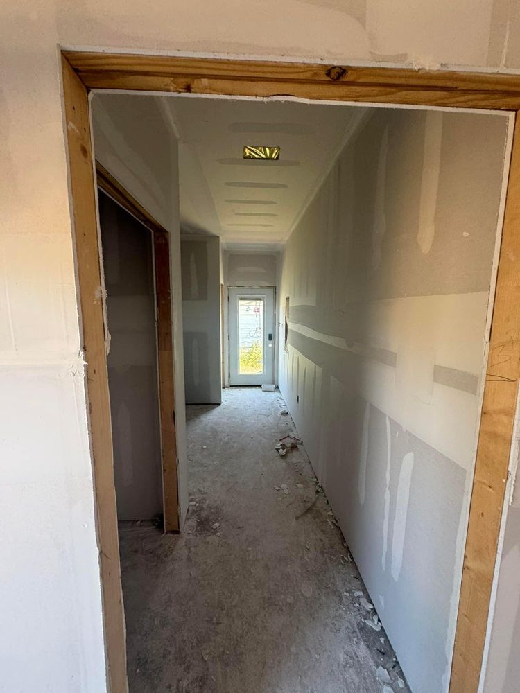 A long hallway with drywall on the walls and a door.