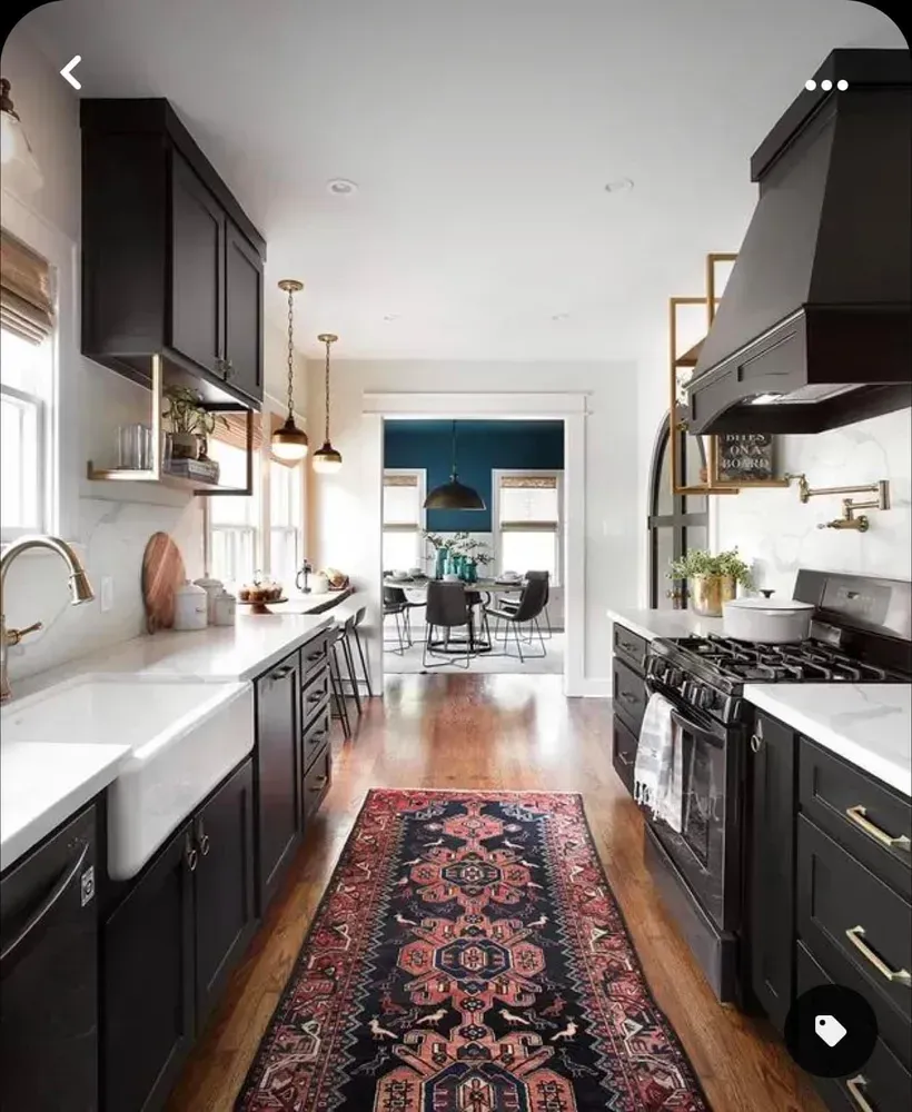 A kitchen with black cabinets and a rug on the floor