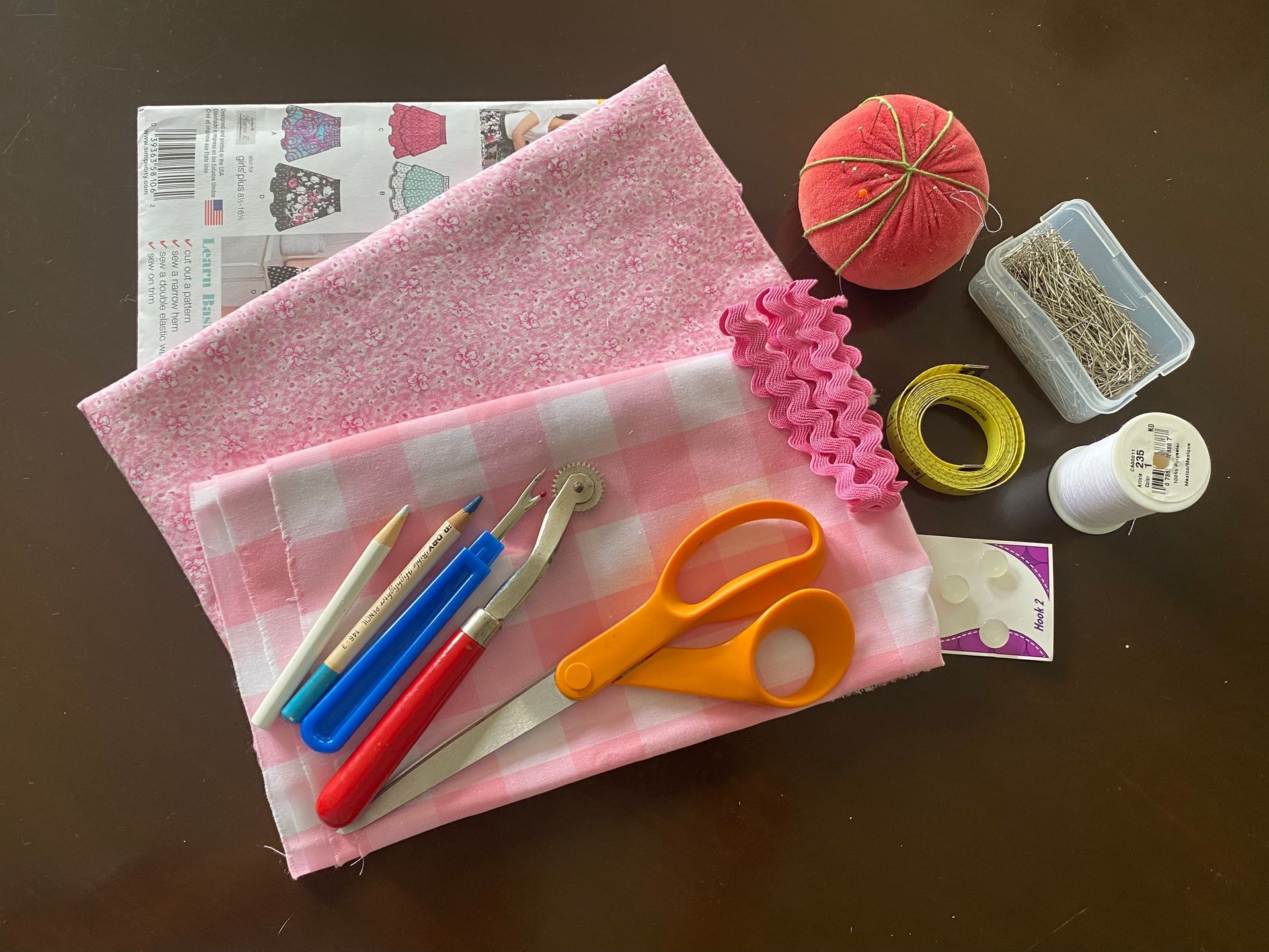 Two pieces of pink fabric, pattern, sewing tools and notions 