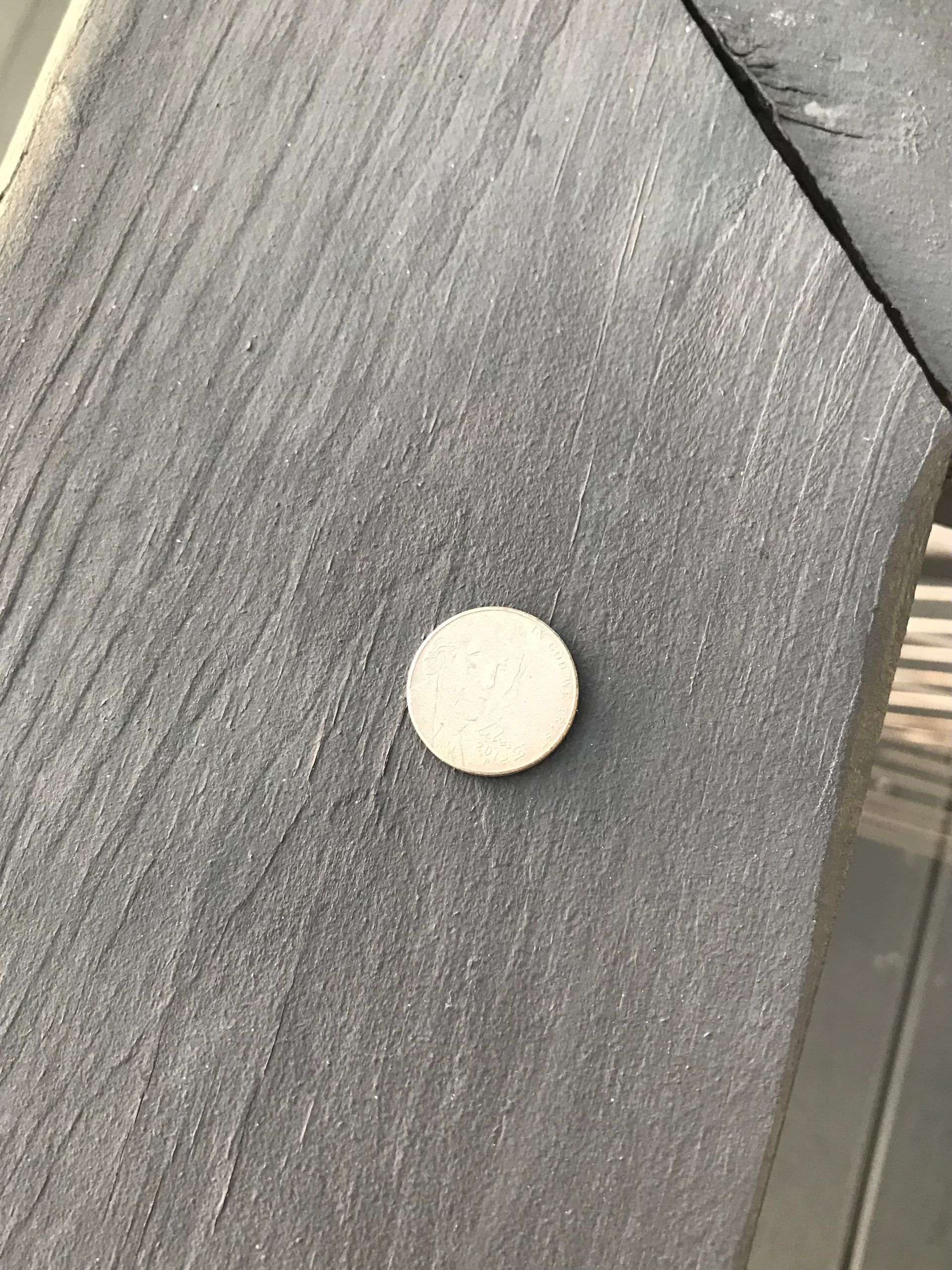 Shiny nickel laid on a gray deck railing