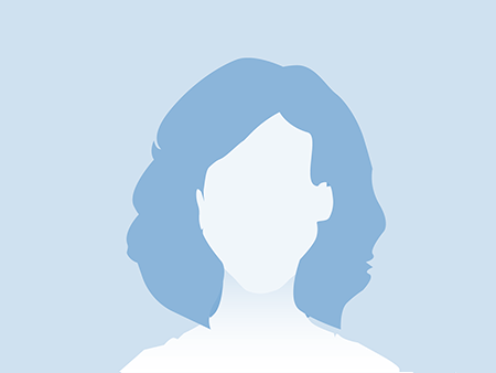 Eine Frau mit Brille und blauem Kittel lächelt vor einer Blumenvase.