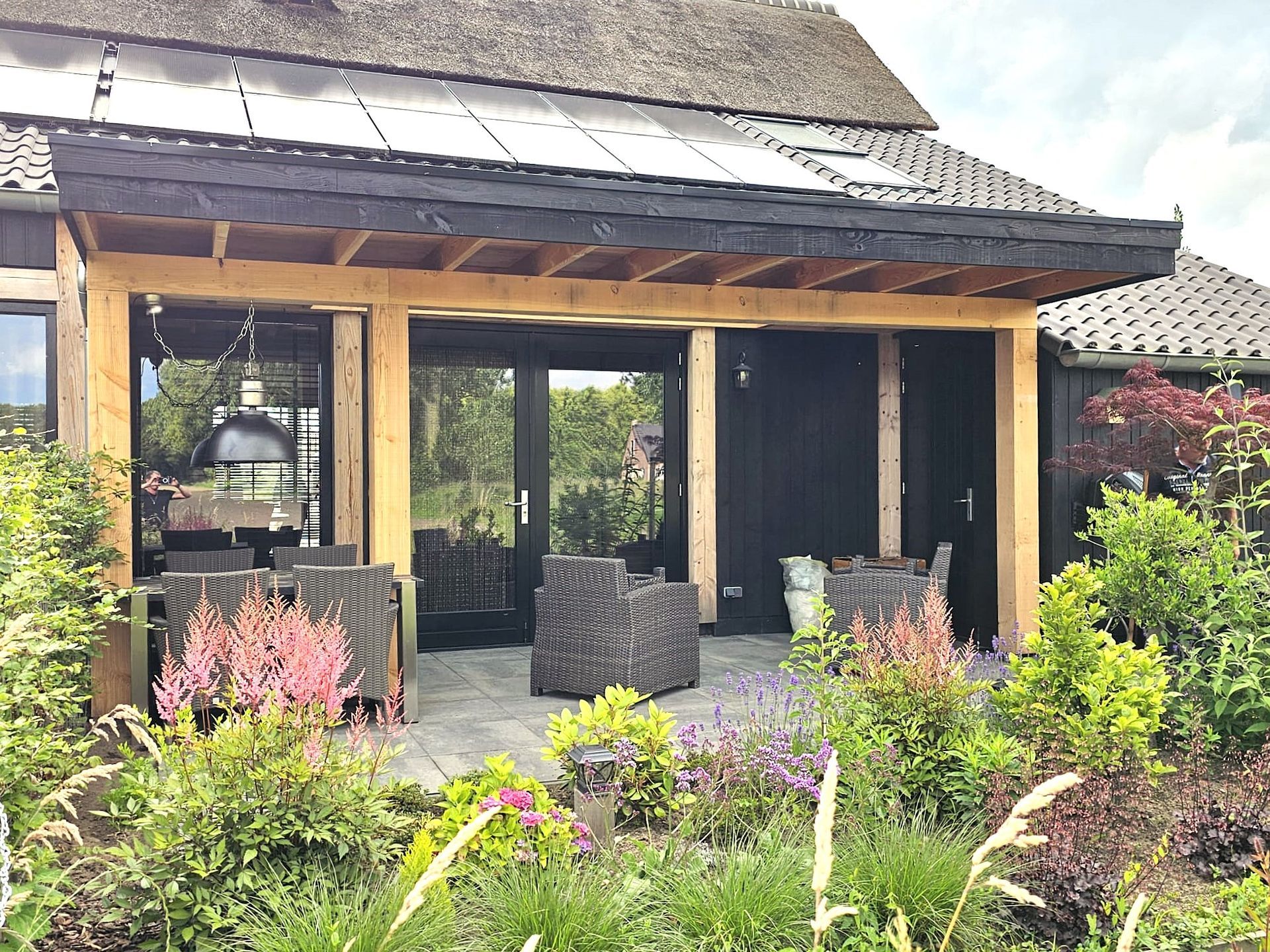 Overdekt terras met zitgelegenheid en omringende tuin.