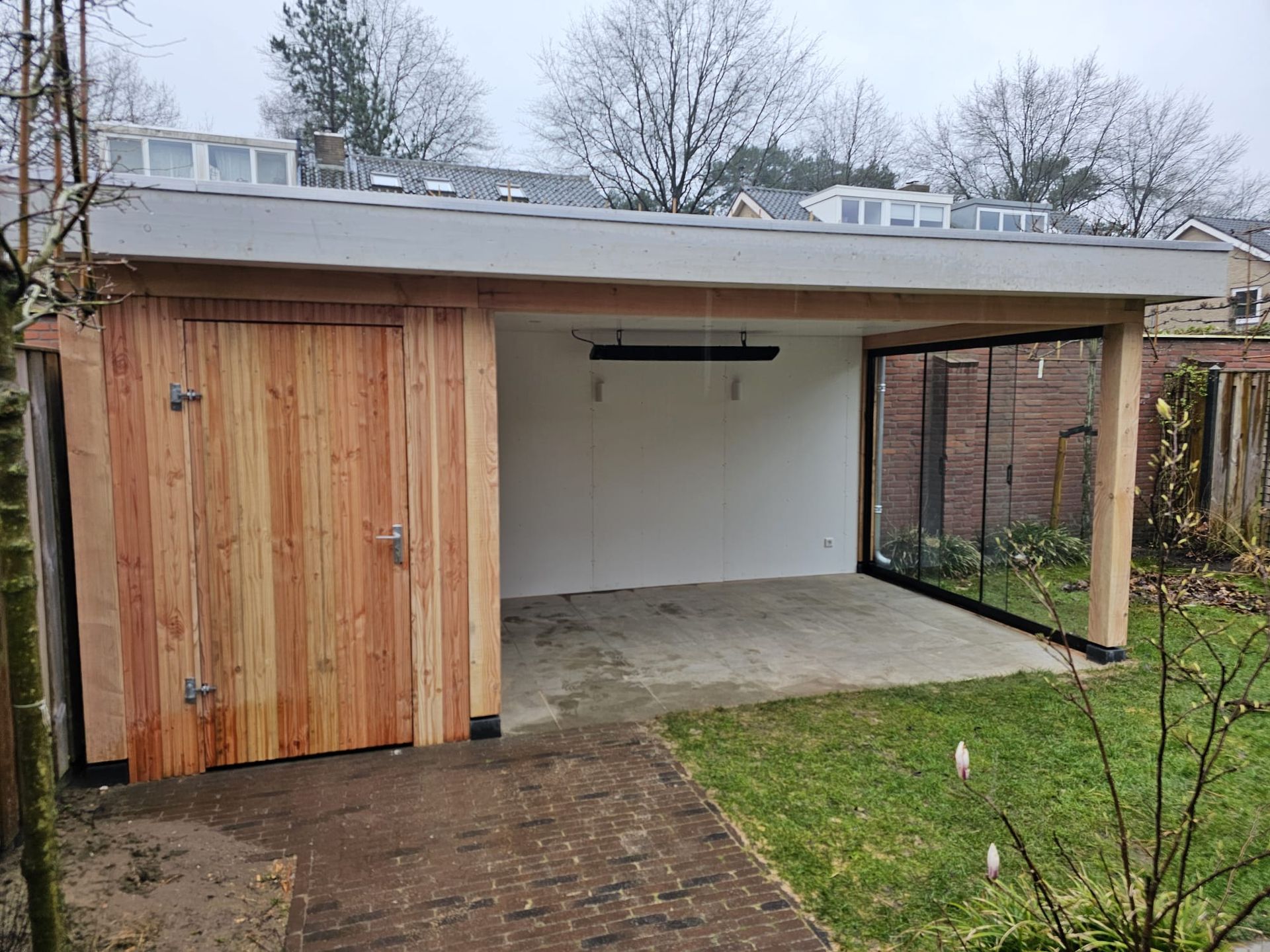 Een houten overkapping met een glazen schuifwand.