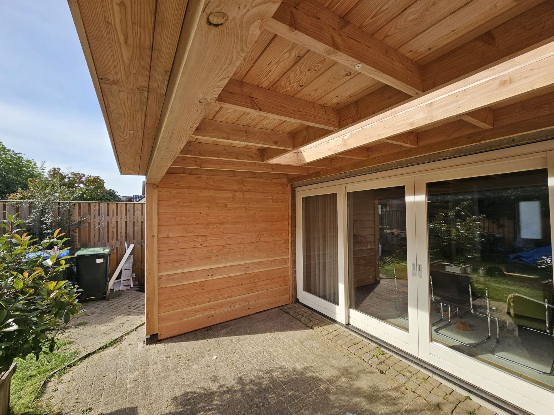 Een houten gebouw met glazen schuifdeuren en een houten dak.
