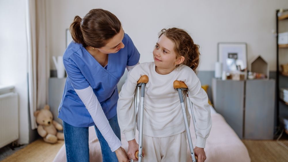 A nurse is helping a little girl with crutches.