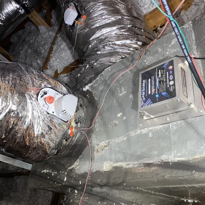 HVAC system components in an attic, including ducts, a control box, and motorized dampers.