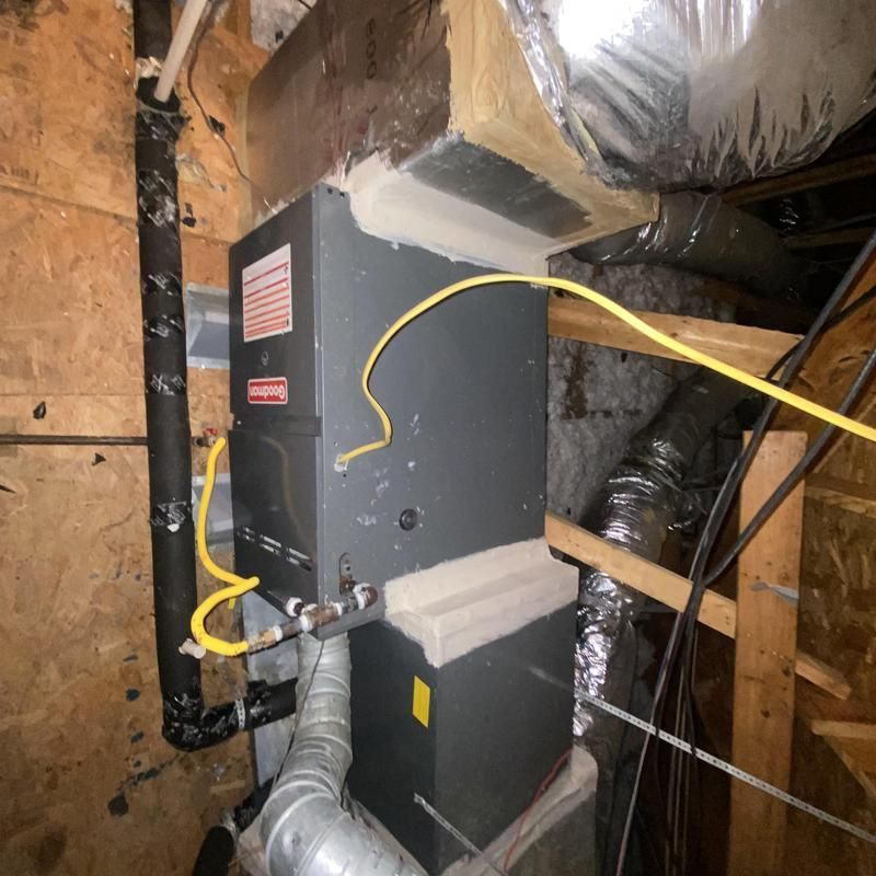 Furnace unit in a utility room with yellow electrical wiring and ductwork.