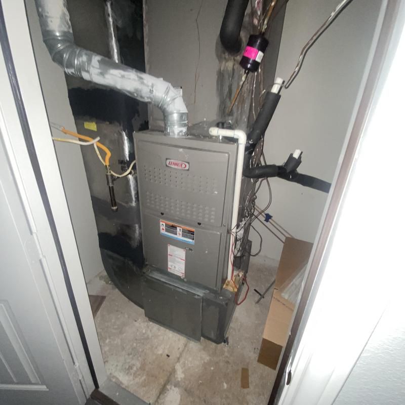 A Lennox furnace in a small utility closet, with ductwork and pipes visible.