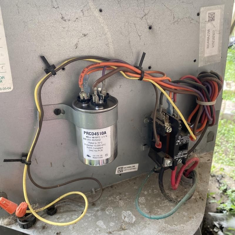 Air conditioner capacitor and wires on metal panel.