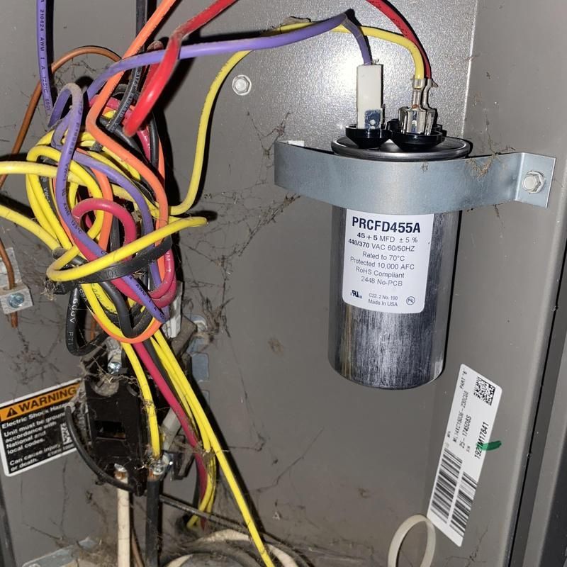 Electrical components of an AC unit, wires of various colors connected to a capacitor.