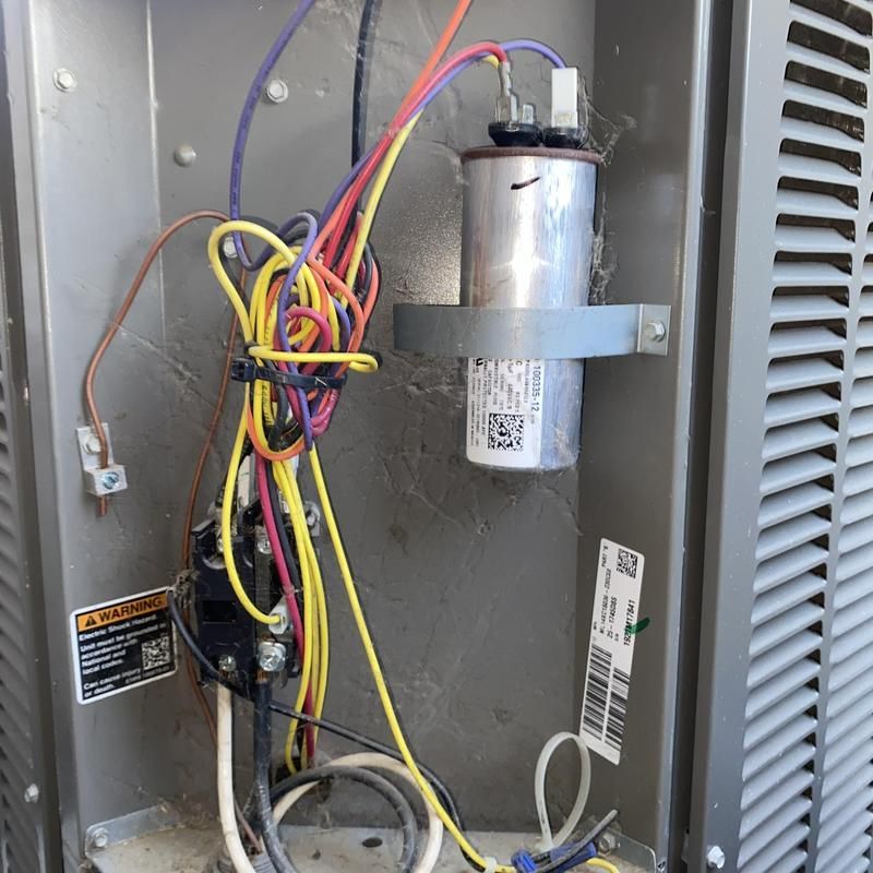 Air conditioner components, wires, capacitor, and contactor inside a metal unit.