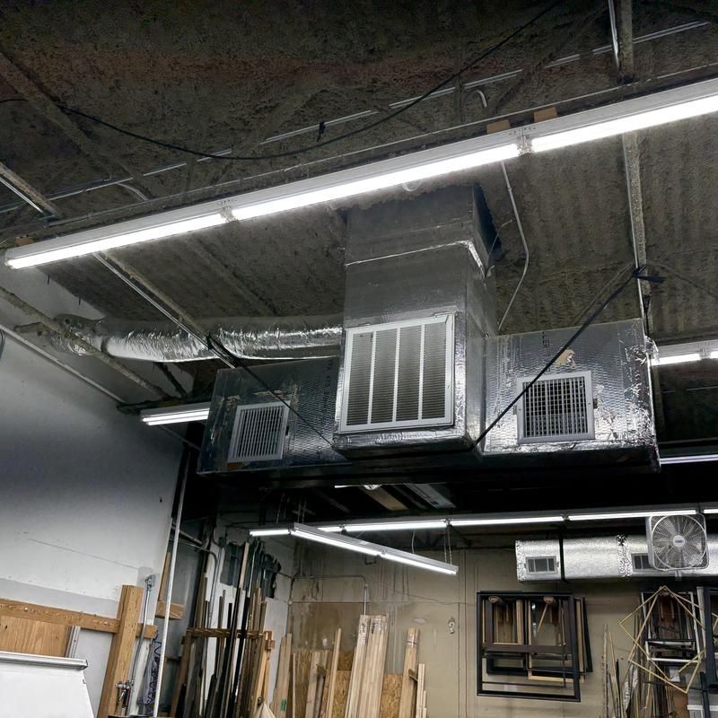 Workshop interior with hanging ventilation system and fluorescent lights.