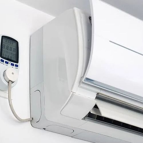 White air conditioner unit on a wall with a power meter displaying numbers.