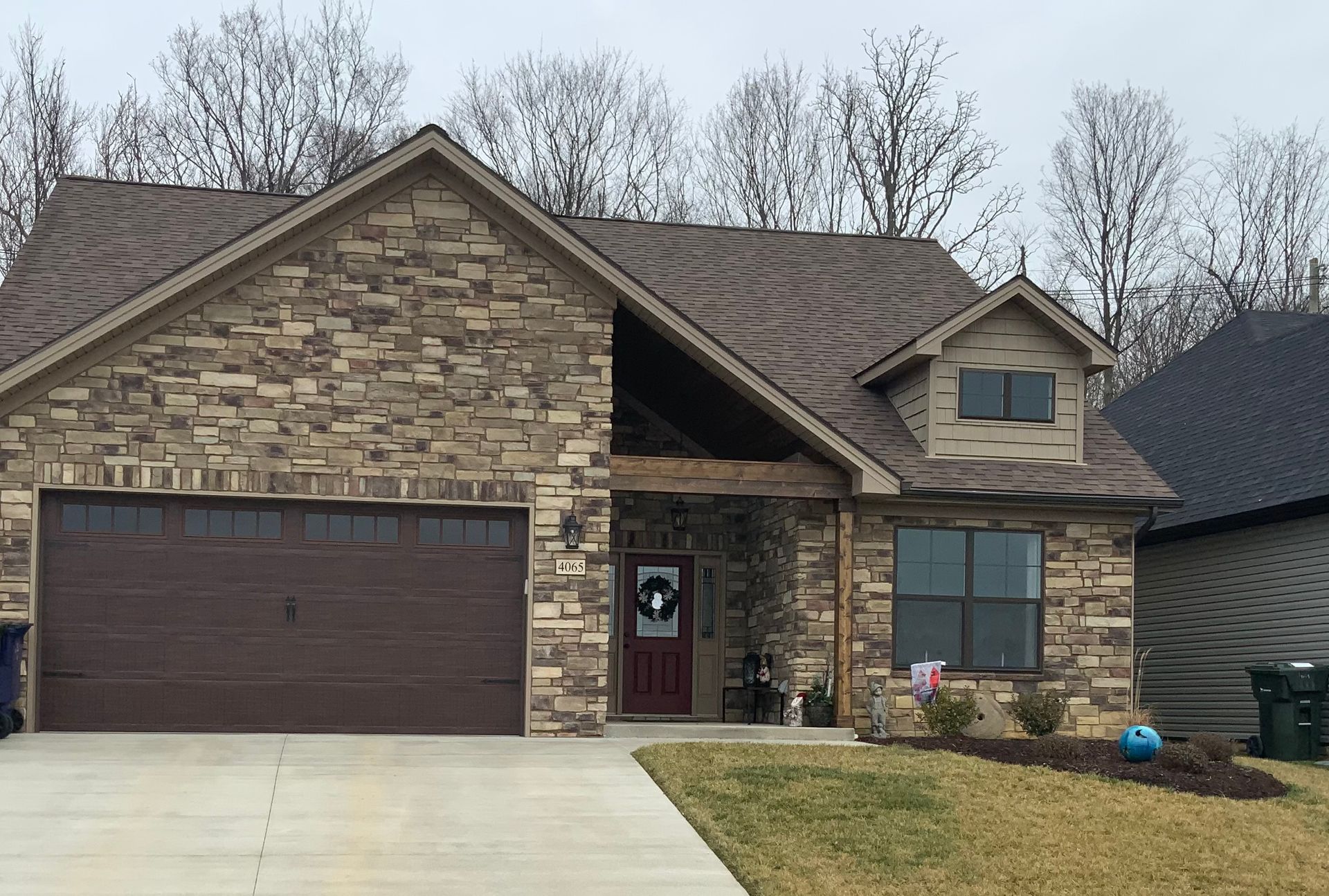 A brick house with a brown garage door and a red door