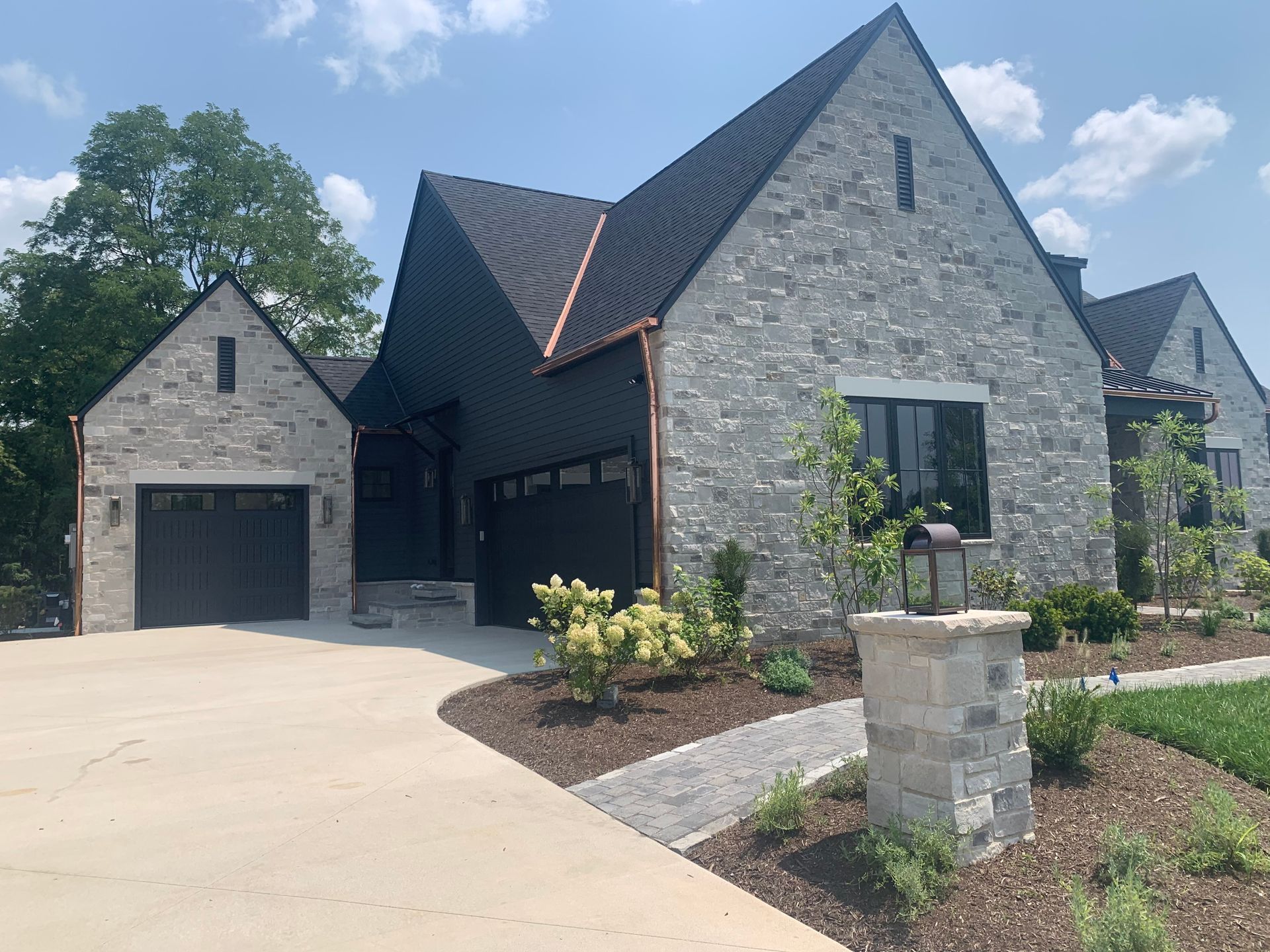 A large brick house with a black roof and a black garage door.