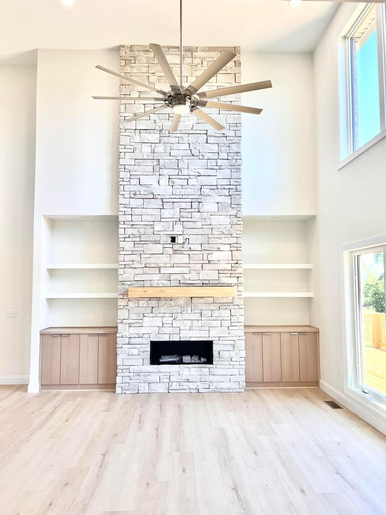 A living room with a fireplace and a ceiling fan.