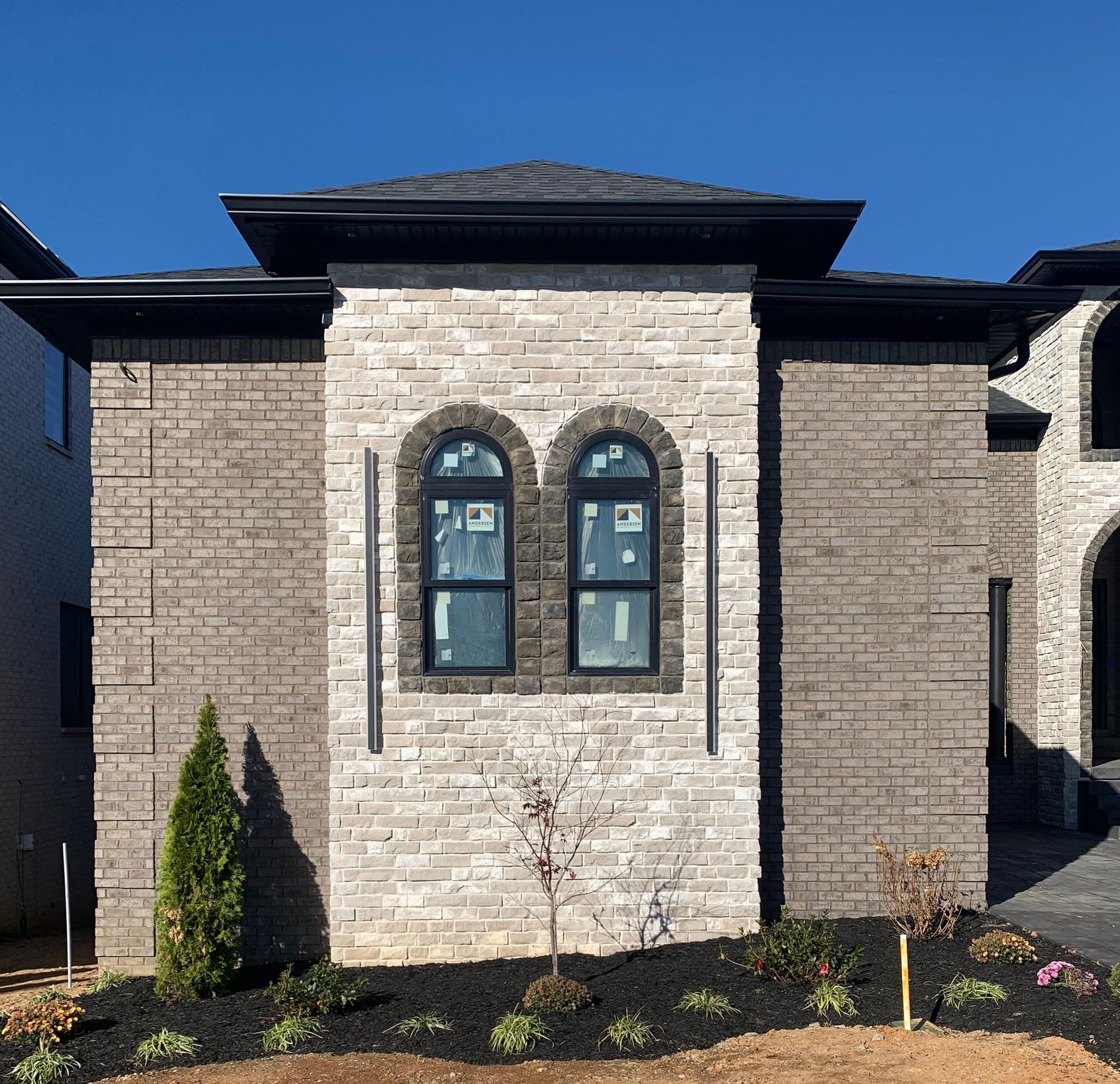 A brick house with arched windows and a blue sky in the background