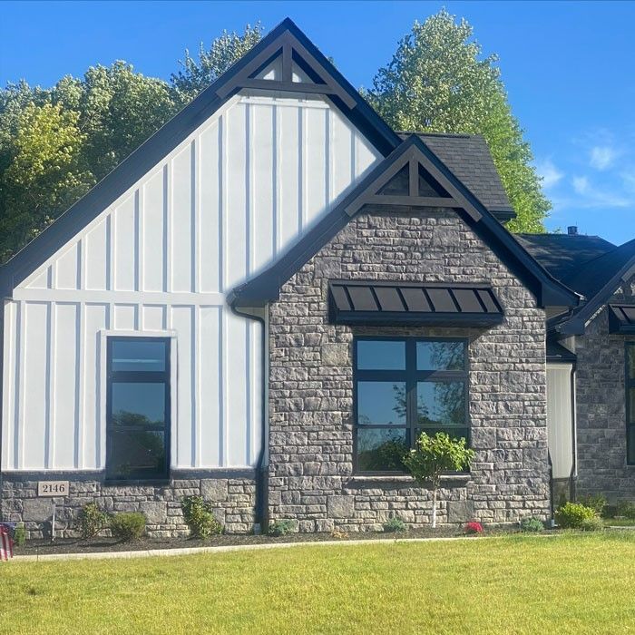A stone house with black windows and a black roof
