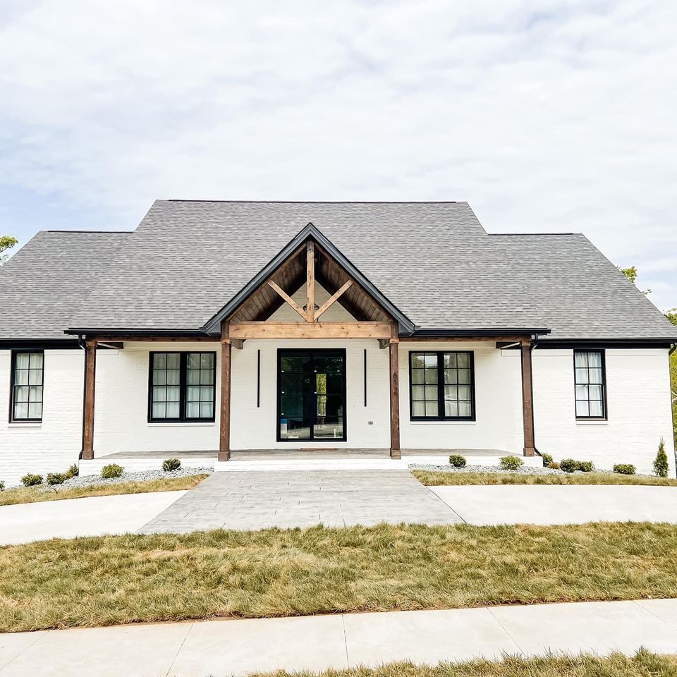 A white house with a gray roof and a wooden porch.