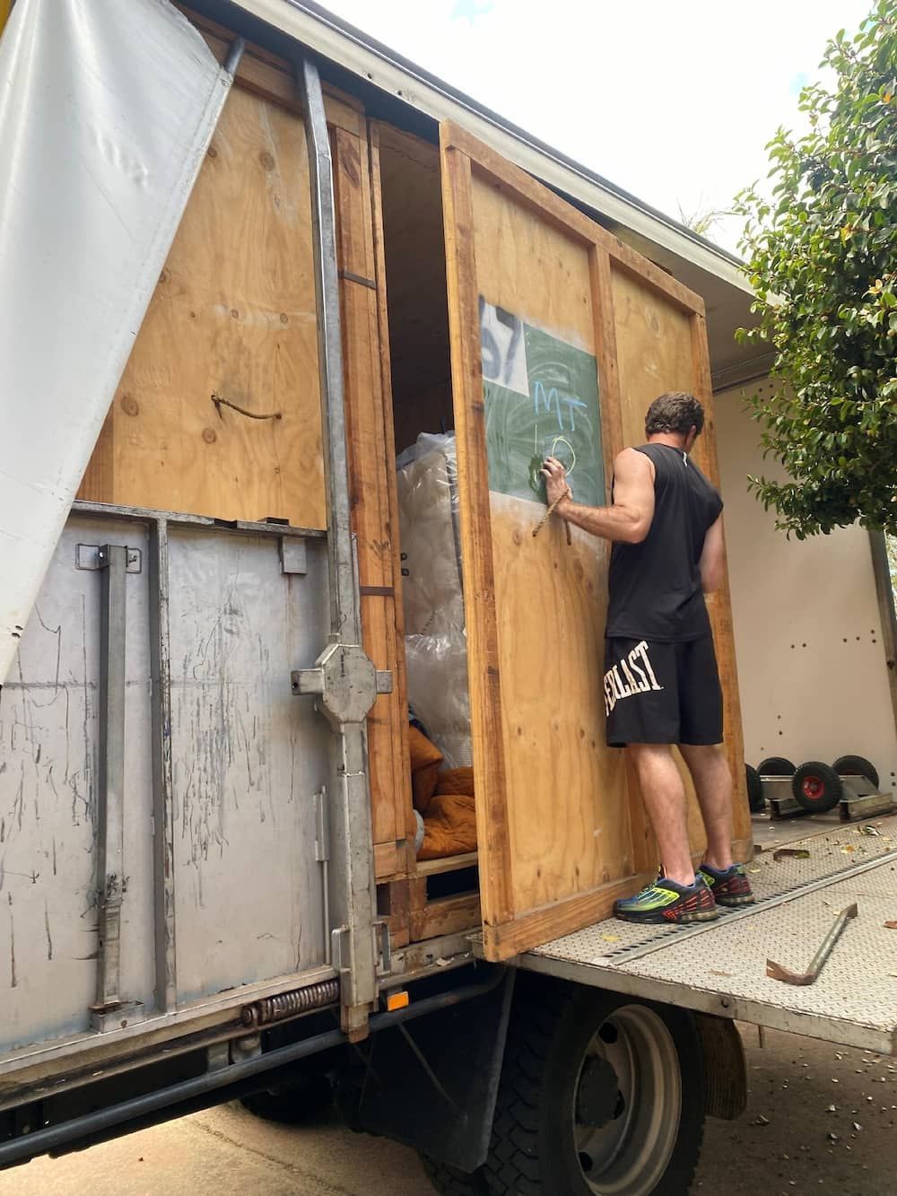 A Man is Standing on the Back of a Moving Truck — Ballina Removals & Storage in Alstonville, NSW