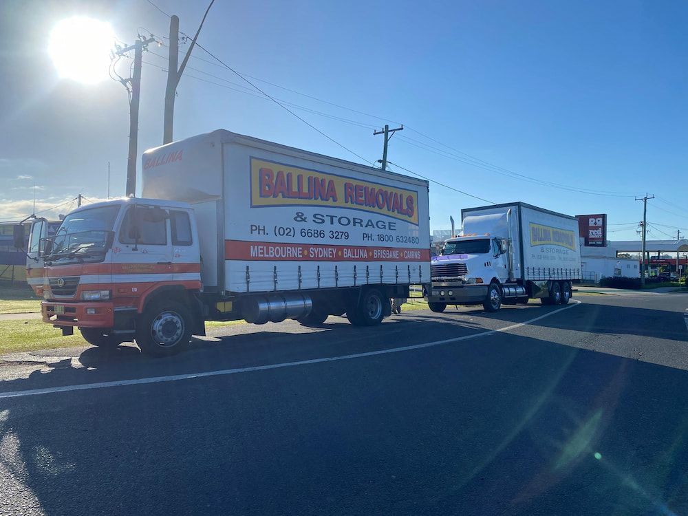 Two Moving Trucks Are Parked on the Side of the Road — Ballina Removals & Storage in Alstonville, NSW
