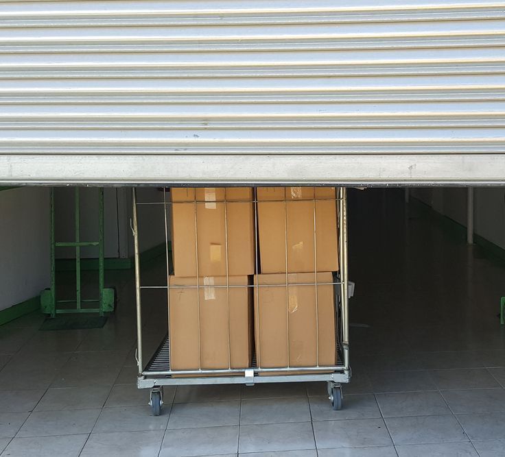 Two Cardboard Boxes Are on a Cart Under a Garage Door — Ballina Removals & Storage in Alstonville, NSW