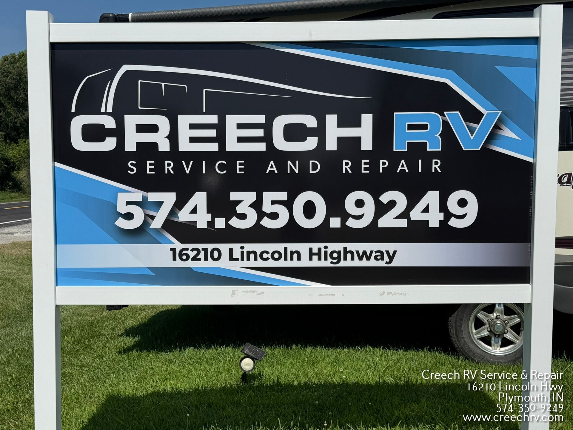 Sign for Creech RV Service and Repair with phone number and address, blue and black background.