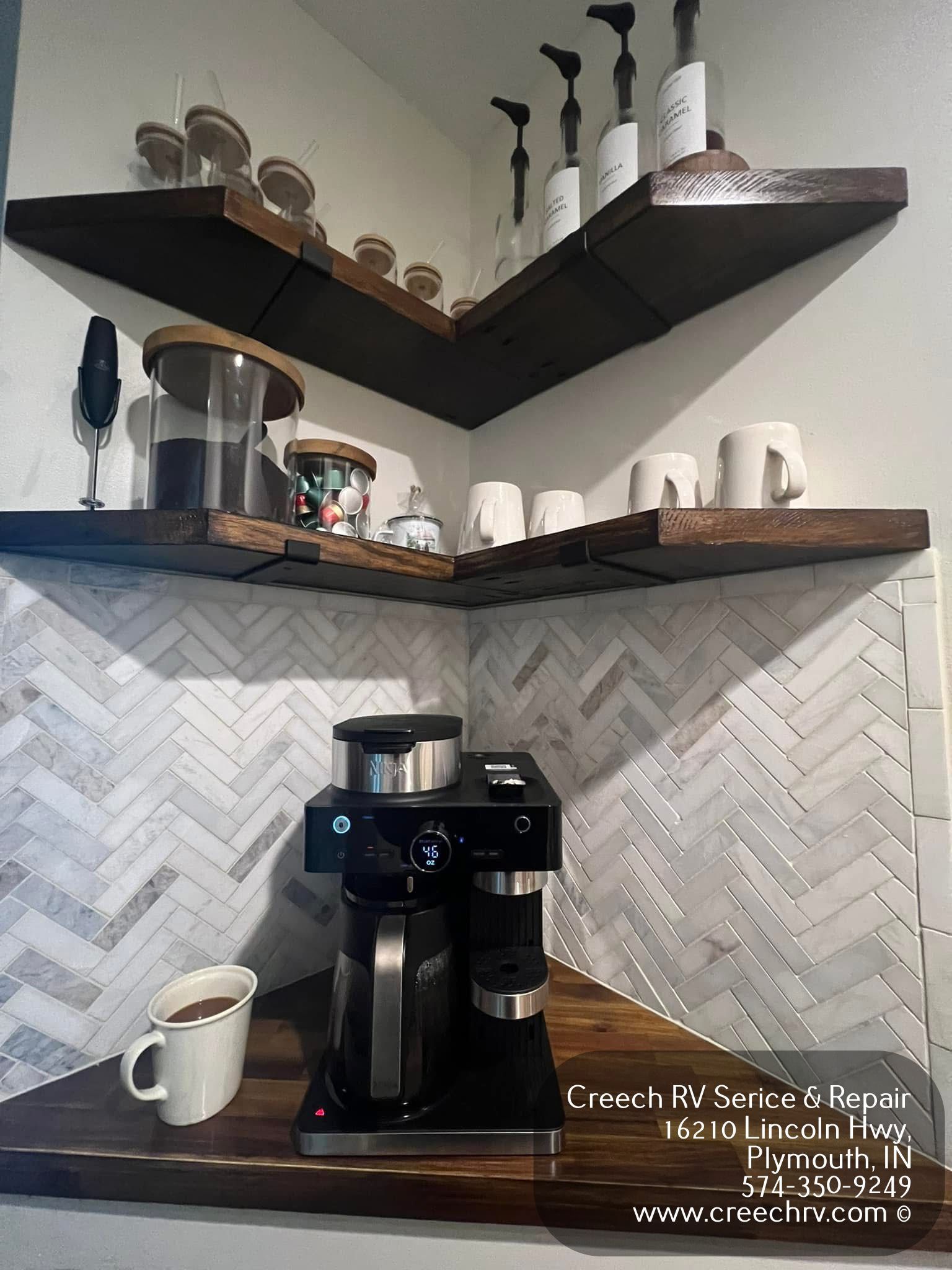 Coffee station in a corner, with shelves, coffee maker, mugs, and a milk container on the counter.