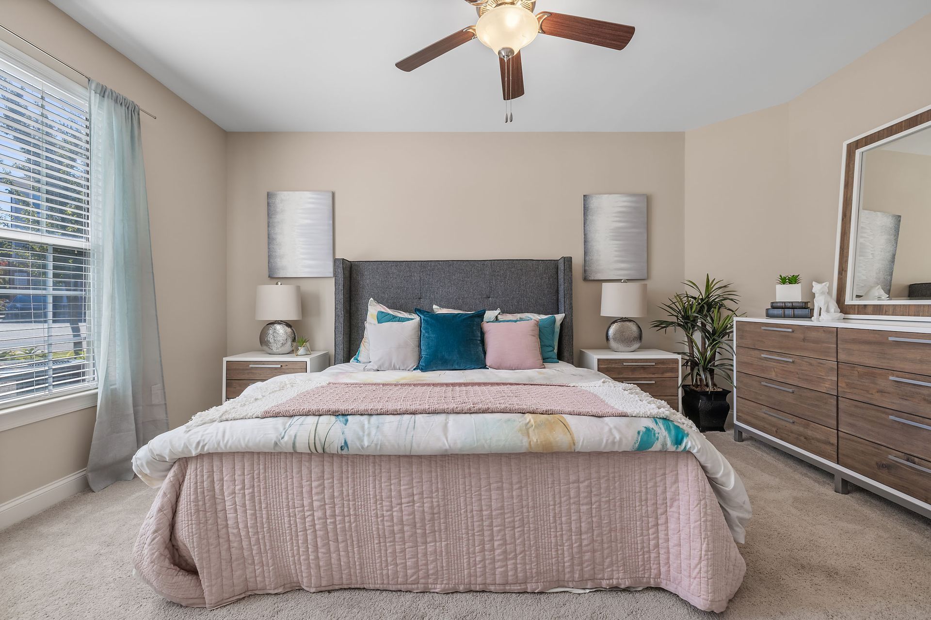A bedroom with a bed, dresser, mirror and ceiling fan at Marquis Ellis Crossing offers apartments for rent near Duke University, Durham, NC.