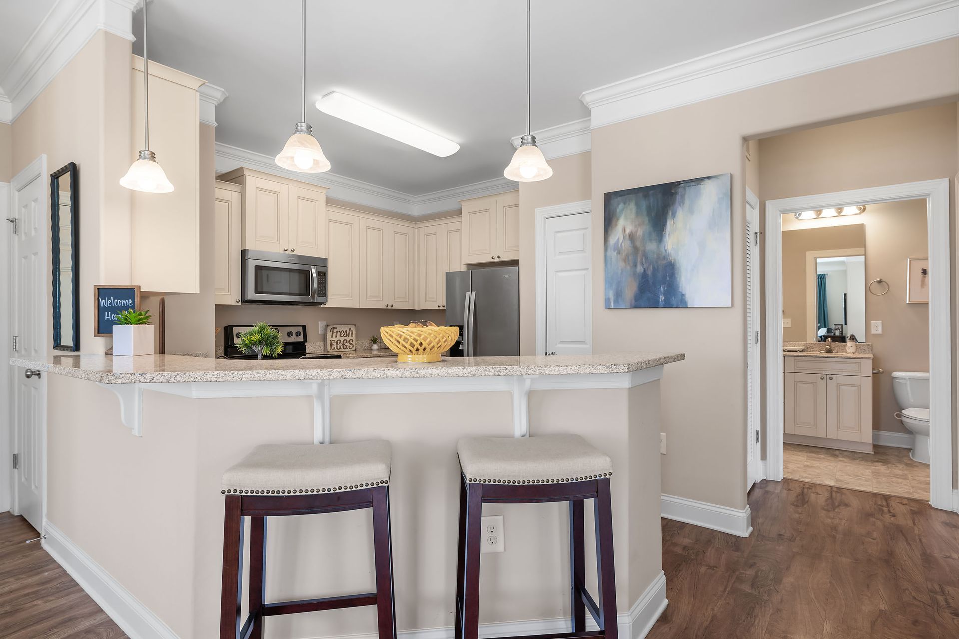 A kitchen with a bar, stools, a refrigerator and a microwave at Marquis Ellis Crossing offers apartments for rent in Durham, NC.