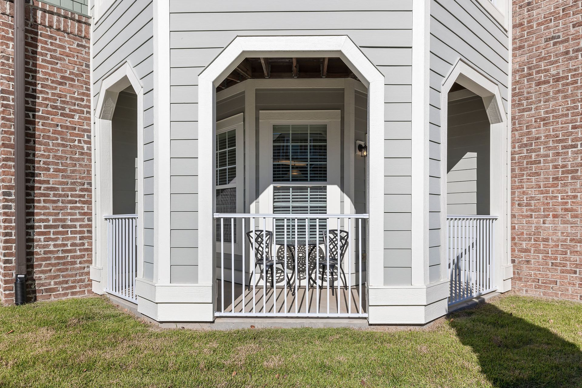 The front of a brick house with a porch and a white railing at Marquis Ellis Crossing offers apartments for rent in Durham, NC.