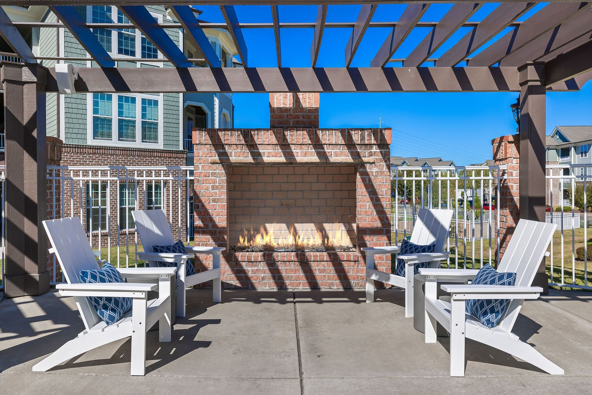 A brick fireplace is surrounded by white chairs under a pergola at Marquis Ellis Crossing offers pet-friendly apartments for rent in Durham, NC.