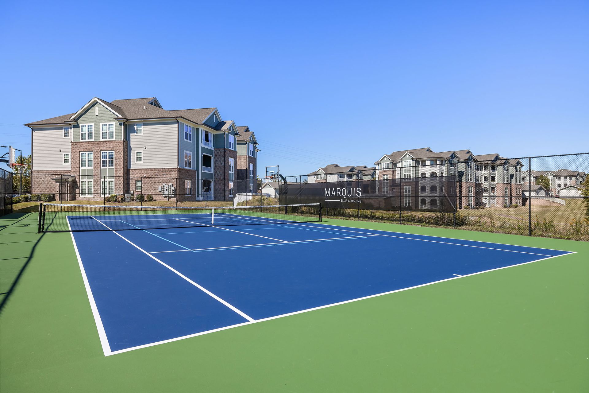 A tennis court with apartment buildings in the background at Marquis Ellis Crossing offers apartments for rent in Durham, NC.