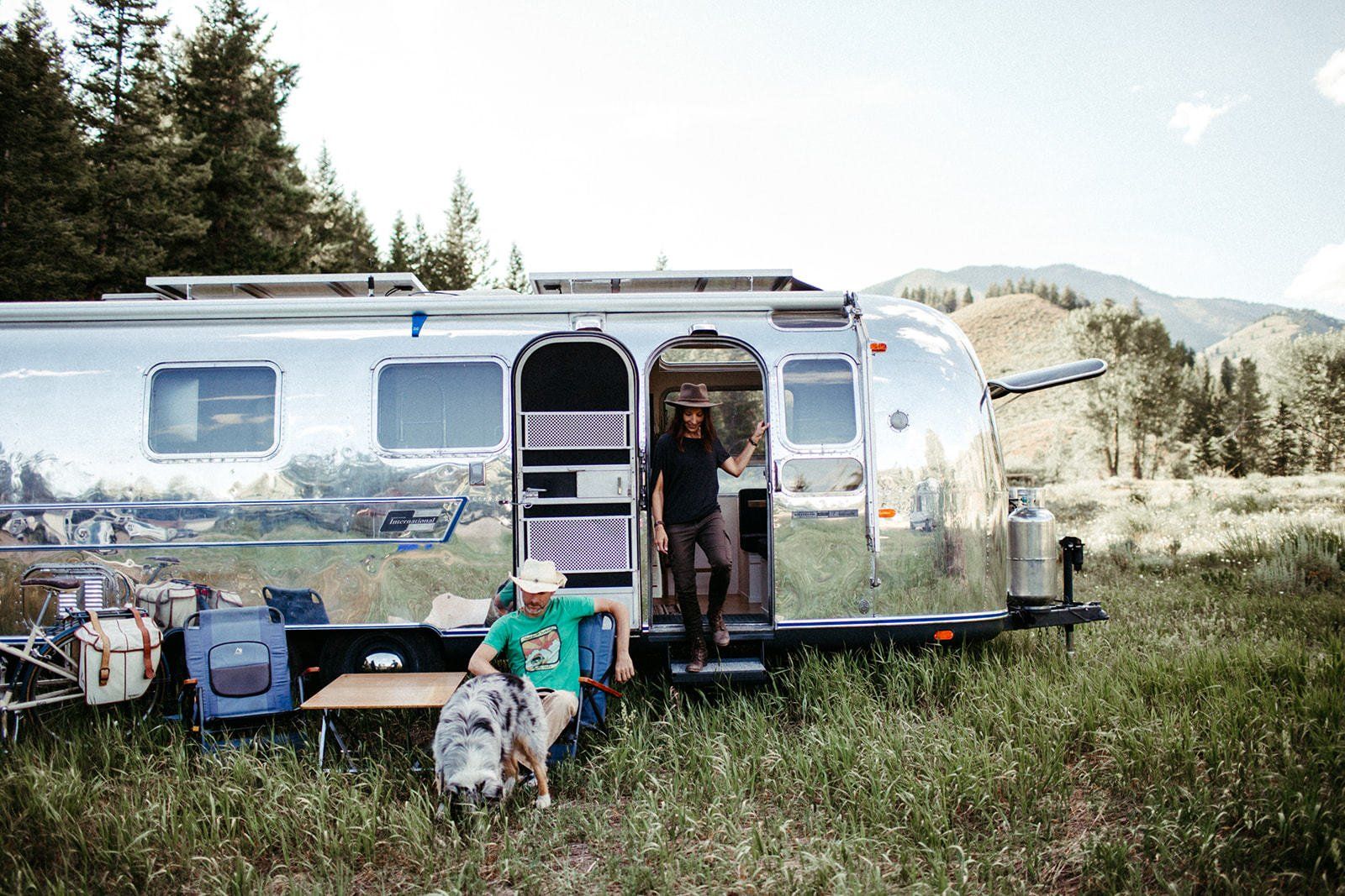 Shiny vintage airstream with a guy and girl hanging out in front of it