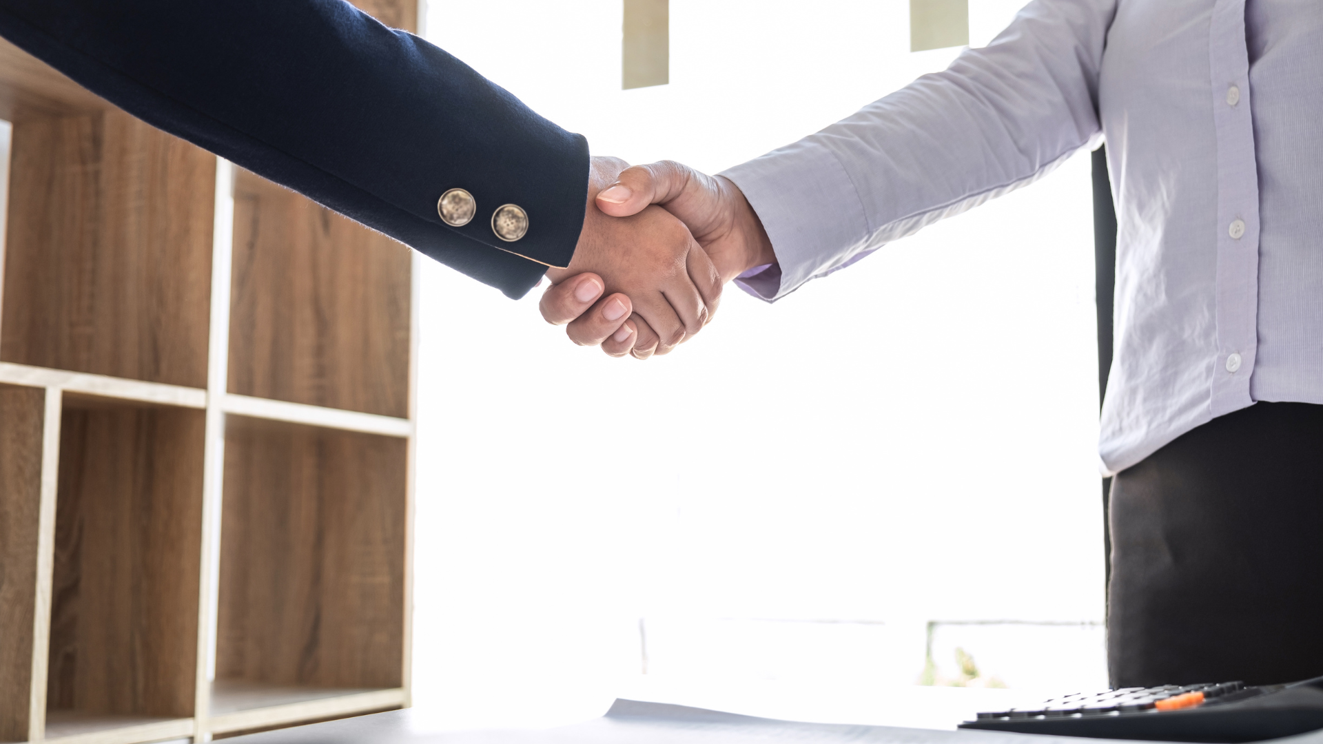 Two people shaking hands in an office, symbolizing a business deal or agreement.