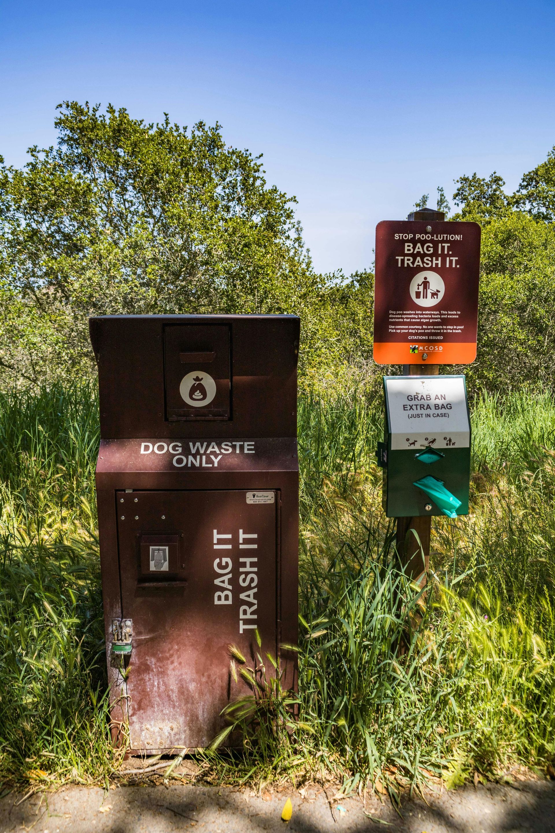 A trash can is sitting next to a sign that says dog waste only.