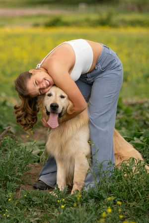 A woman is hugging a dog in a field of flowers.