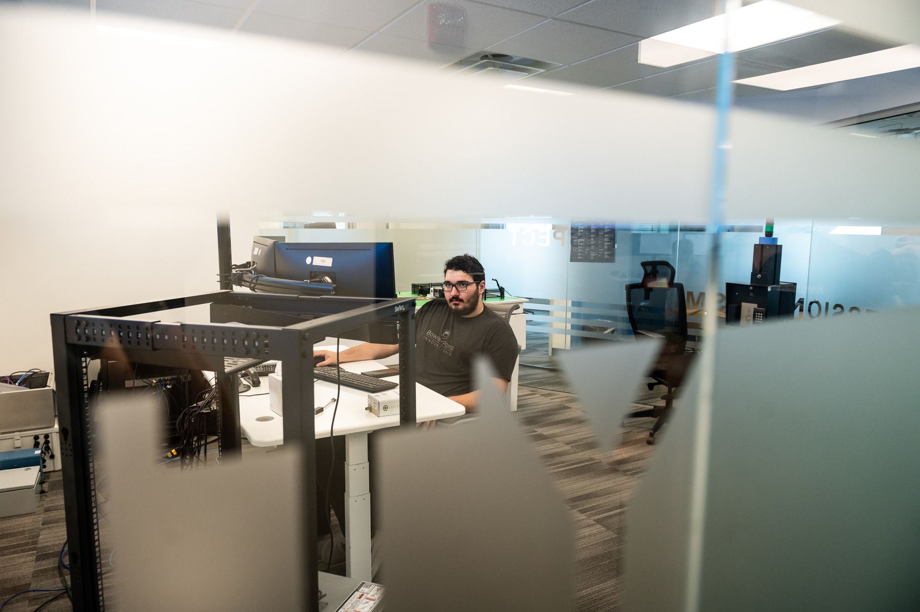 Bowler Pons Employee working at a desk in an office behind a frosted glass wall.