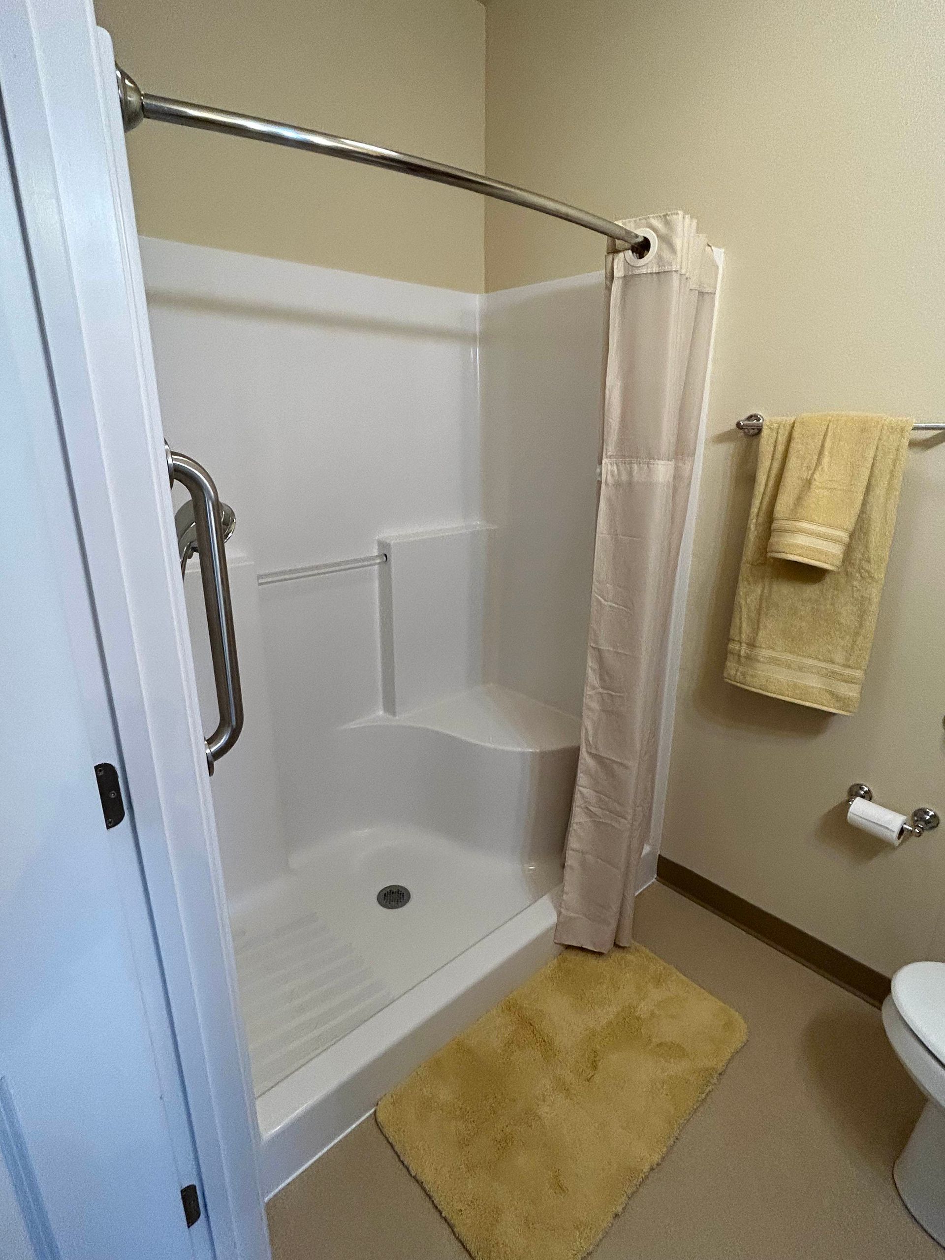 A bathroom with a shower , toilet , and towels.