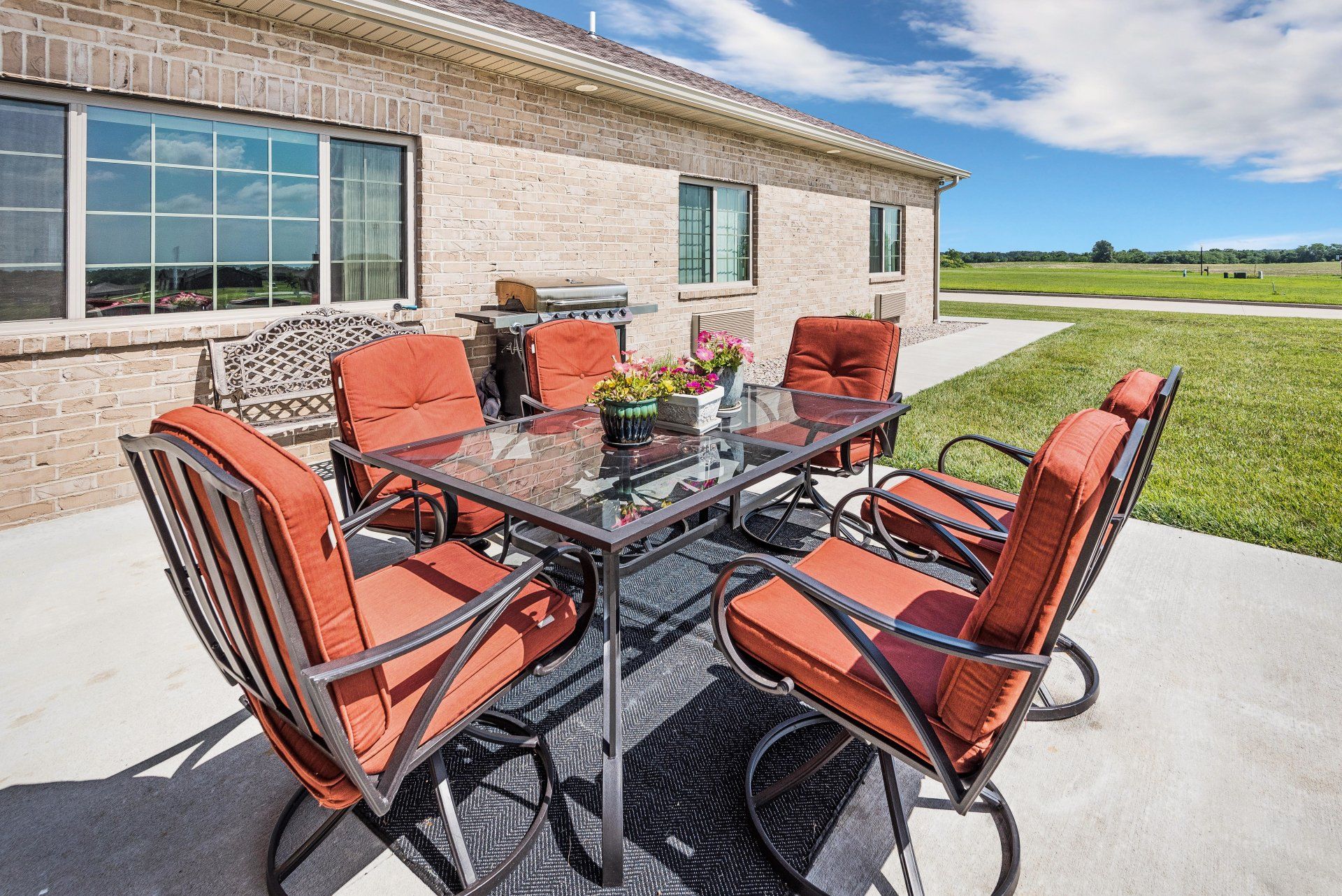 A patio with a table and chairs in front of a brick house.