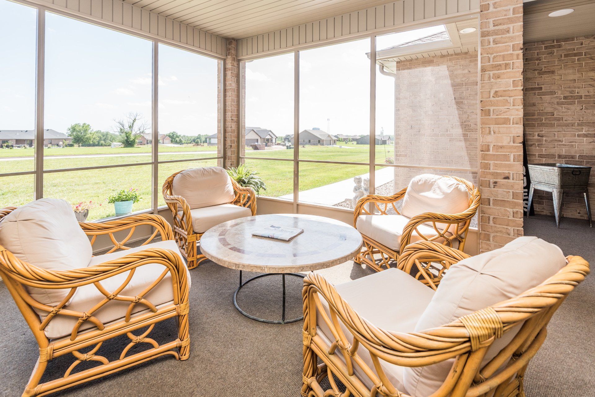 A screened in porch with wicker furniture and a table.