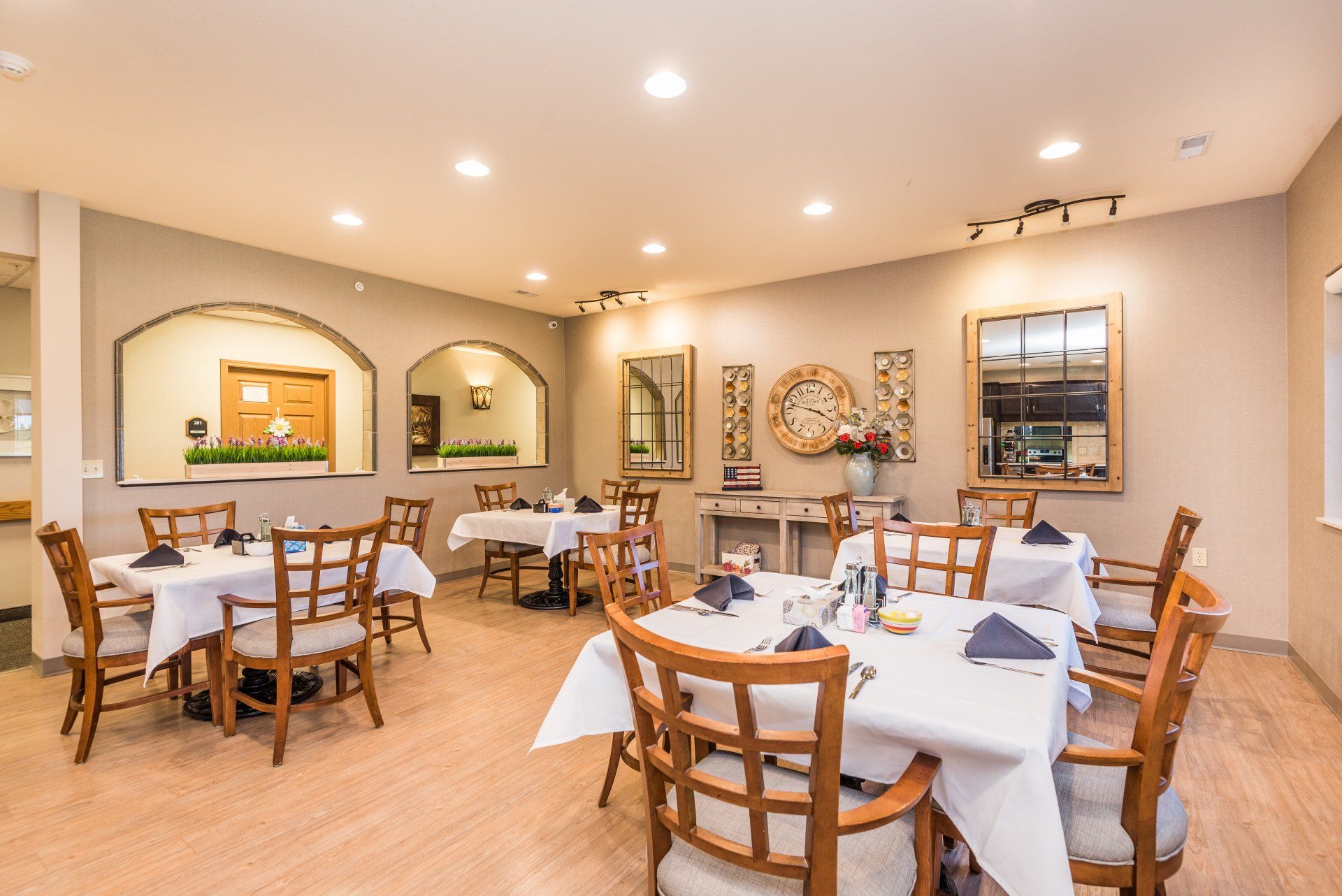 A large dining room with tables and chairs and a clock on the wall.